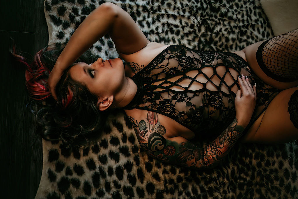 A woman in black lace lingerie lays on a cheetah print blanket in a studio a la mode intimates