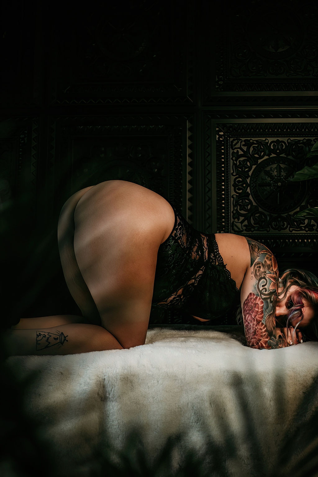 A woman in black lace lingerie lays on a bed on her knees annapolis yoga studios